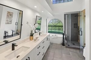 Elegant bathroom featuring a soaking bathtub, glass-enclosed shower, large windows for natural light, and an outdoor view—remodeled by a Los Angeles bathroom expert.